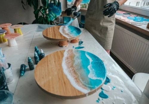 Resin art cutting boards with ocean-inspired blue and white wave designs being created during the Resin Cutting Boards & Coasters workshop at the Artist Outpost in Ocean Beach.